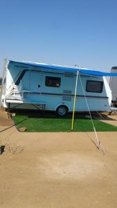 ein blau-weißer Wohnwagen, der auf einem Feld parkt in der Unterkunft קרוואן על החוף in Eilat