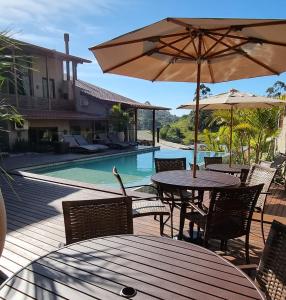 een tafel en stoelen met een parasol en een zwembad bij Valle Paradiso in Praia do Rosa