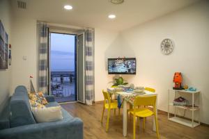 a living room with a couch and a table with yellow chairs at Filoblu appartamento Formia in Formia