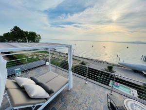 バルドリーノにあるBardolino Luxuryのソファ付きのバルコニーから水辺の景色を望めます。
