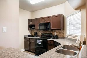 a kitchen with brown cabinets and a sink and a stove at Uptown Escape - Modern, 1BD Apt near the Galleria in Houston
