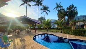 a swimming pool in front of a house with palm trees at De Bem K Vida in Ubatuba