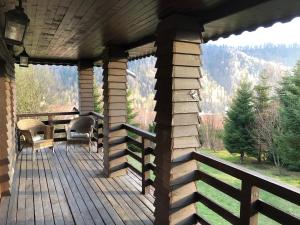 eine Holzterrasse mit einem Tisch und Stühlen darauf in der Unterkunft Imperial F Villa in Azuga