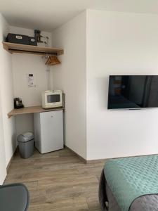 a small room with a bed and a microwave at Les Chambres de Lily 2 in Lorgies