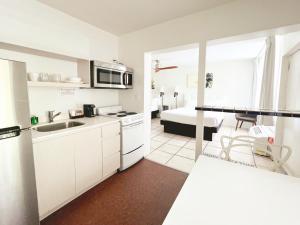 a white kitchen with a sink and a microwave at Tropi Rock in Fort Lauderdale