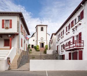 a church with a steeple in the middle of two buildings at Auberge hiribarren in Biriatou