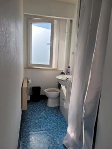 een badkamer met een toilet, een wastafel en een raam bij 2 Bedroom Apartment in De Haan in De Haan