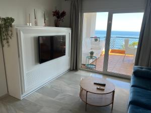 a living room with a tv and a couch and a table at MI CAPRICHO, Beach Front Apartment P14 3ºB in Mijas Costa +40 photos