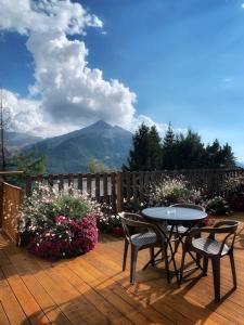 eine Terrasse mit einem Tisch, Stühlen und Blumen in der Unterkunft Hotels Les Catrems & Le Montagnou in Orcières