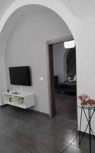 a living room with an archway with a television and a table at Fortino vecchio apartment in Catania