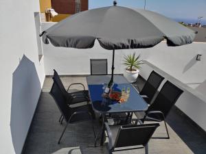 una mesa y sillas con una sombrilla en el balcón en LUXURY DUPLEX ATLANTIC FOUR SEASONS, en Santa Cruz de Tenerife