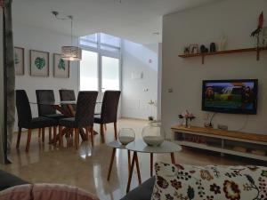 Una sala de estar con una mesa y sillas y un televisor. en LUXURY DUPLEX ATLANTIC FOUR SEASONS, en Santa Cruz de Tenerife