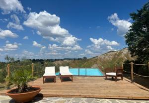 una terraza de madera con 2 sillas y una piscina en Podere Doccia di Sopra, en Volterra