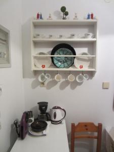 a kitchen counter with cups and dishes on shelves at Katerina Apartments in Triovasálos
