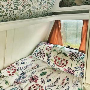 Cama en habitación pequeña con papel pintado con motivos florales en Cosy Caravan at Carrigeen Glamping, en Kilkenny
