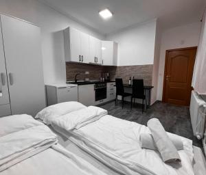 a bedroom with two beds and a kitchen with a table at Stan na dan Sebastijan in Banja Luka