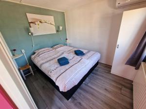 um quarto com uma cama com duas toalhas azuis em De droom van Zeeland met jacuzzi & Finse sauna em Sint-Annaland