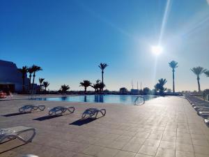 - une piscine avec un groupe de chaises et de palmiers dans l'établissement MARAVILLA Suite 140 m2 - 3 Bedrooms, Heated Pool, à Costa del Silencio