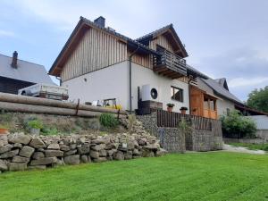 a large white house with a stone wall at Apartament u Ewki in Rdzawka