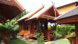 a wooden house with a garden in front of it at Golden Teak Resort Baan Sapparot in Kamala Beach +6 photos