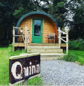 a small log cabin with a green door and a sign at Carrigeen Glamping in Kilkenny