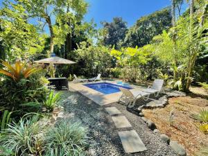 un jardín con piscina, sillas y árboles en Casa Mambo Pool House, en Puerto Viejo