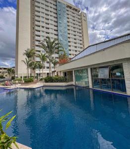 a large blue swimming pool in front of a building at Flat Rio Centro - Jeunesse Arena - Barra da Tijuca - Projac - TV Globo - Parque dos Atletas in Rio de Janeiro