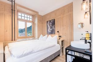 a bedroom with a large white bed and a sink at ALPINE INN Davos in Davos
