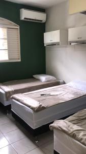 three beds in a room with green walls at Hostel Office- Hospedagem Climatizada quartos e apartamentos privativos in Extrema
