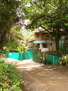 a house with a blue fence next to a road at Burnt Toast Surfcamp in Nosara