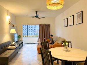 a woman sitting in a living room with a table at BayView Suites Port Dickson By MAISON in Port Dickson