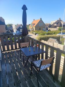 a table and chairs on a deck with an umbrella at Pension Canberra in Bergen aan Zee
