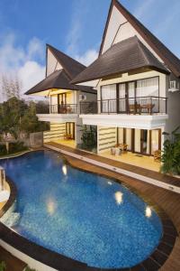 a house with a swimming pool in front of it at Flamingo Dewata Suite in Uluwatu