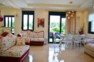 Belle Verte Villa Maleme في ماليم: غرفة معيشة مع أريكة وطاولة وكراسي