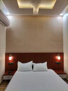 a bedroom with a large white bed with two pillows at Anushangi Hotel in Hisār