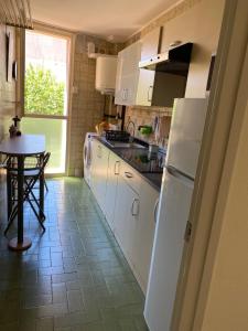 cocina con nevera blanca y mesa en Luminoso apartamento en Canet de Mar cercano a la playa y a Barcelona, en Canet de Mar