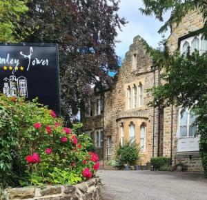 un bâtiment en pierre avec un panneau en face de celui-ci dans l'établissement Farnley Tower Guesthouse, à Durham