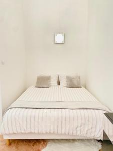 Ce lit se trouve dans une chambre dotée d'un mur blanc. dans l'établissement LYON Full Entier Appartement, à Lyon