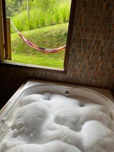 a bath tub filled with white foam in front of a window at Casa do deck - Serra - Santo Antonio do Pinhal in Santo Antônio do Pinhal