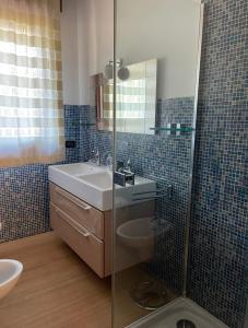 bagno con lavandino e doccia in vetro di Casa Achille a Cavallino-Treporti