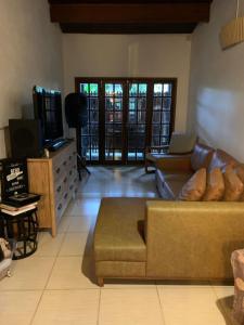 a living room with a couch and a tv at Tropical Casa Ubatuba in Ubatuba