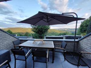 uma mesa de madeira com cadeiras e um guarda-sol numa varanda em TERRASSES DE MALMEDY Triplex 262 SWEET HOME em Malmedy