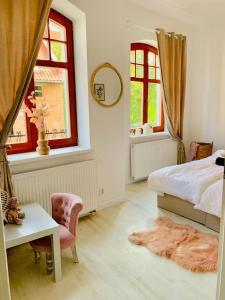 a bedroom with a bed and a table and two windows at Apartamenty Krasicki in Lidzbark Warmiński