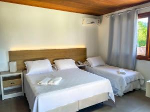 a bedroom with two beds and a window at Pousada Recanto das Flores in Governador Celso Ramos