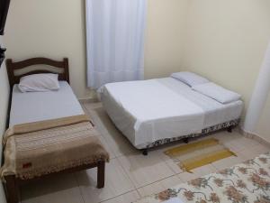 1 dormitorio con 2 camas, ventana y alfombra en Kitnets casa Amarela Imbassai, en Imbassai