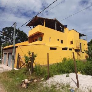 a yellow house sitting on top of a field at Kitnets casa Amarela Imbassai in Imbassai
