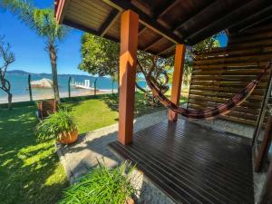 a porch with a hammock and a view of the ocean at Pousada Recanto das Flores in Governador Celso Ramos