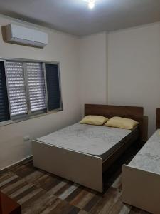 a bedroom with a bed and two windows at Apto Praia Grande in Praia Grande