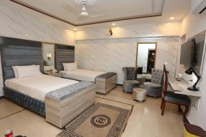 1 Schlafzimmer mit 2 Betten, einem Schreibtisch und einem TV in der Unterkunft Grand Swiss Hotel&Apartment Lahore in Lahore