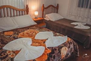 2 camas con toallas encima en una habitación en Pousada Tia Leonor, en Gramado